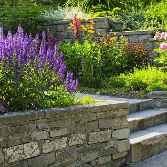 Natural stone landscaping in home garden with steps and flowerbeds